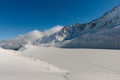 Scenic view of snowcapped mountains against blue sky