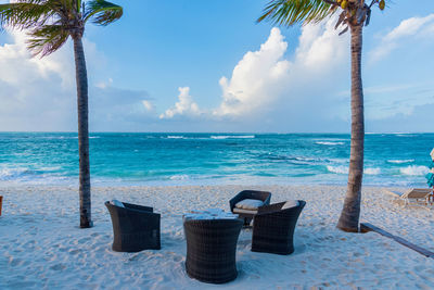 Lounge chairs by swimming pool at beach against sky