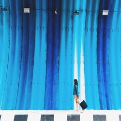 Woman standing against blue wall