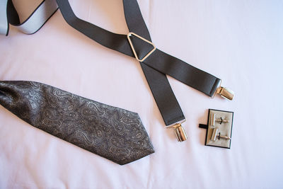 High angle view of suspenders with necktie and cufflinks on fabric