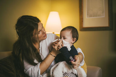 Mother blowing nose of baby girl at home