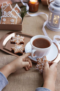 Cropped hand of woman holding coffee on table