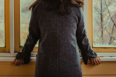 Rear view of man standing against window