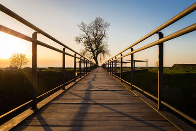 Footbridge against sky during sunset