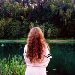 Rear view of woman looking at lake against trees