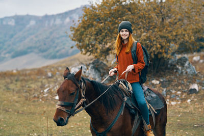 Portrait of smiling young woman riding horse