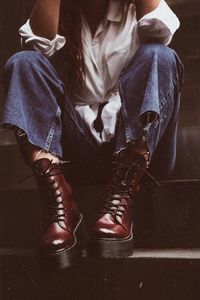 Low section of woman wearing leather shoes while sitting on staircase