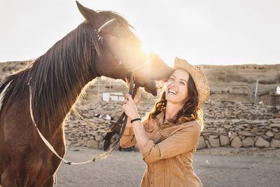 Smiling woman standing by horse