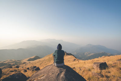 Rear view of man looking at mountains against clear sky