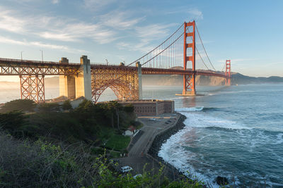 Suspension bridge over sea against sky