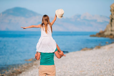 Rear view of father carrying daughter on shoulder