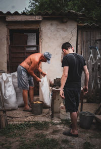 Two men make animal feed into a crusher.