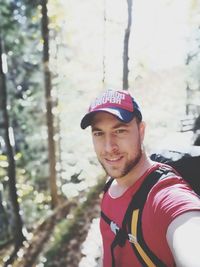 Portrait of young man standing against trees