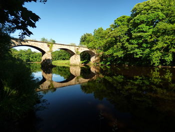 Low angle view of arch bridge over river against sky