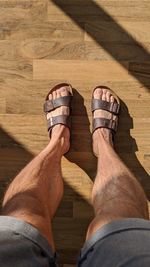 Low section of man wearing shoes on wooden floor