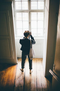 Woman looking through window at home