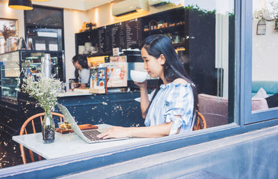 Young woman using mobile phone in restaurant