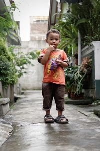 Portrait of cute boy with packets standing on footpath