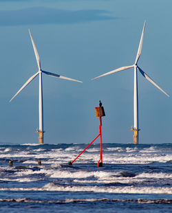 Wind turbines in sea against sky