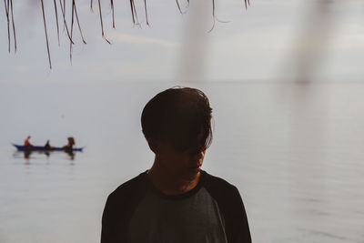 Rear view of man standing against lake