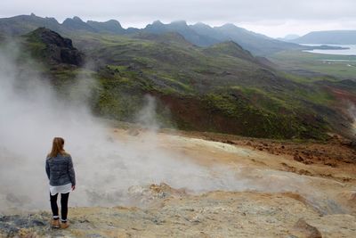 Rear view of woman standing on mountain against sky