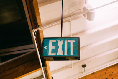 Low angle view of exit sign hanging from ceiling