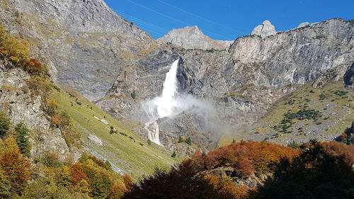 Scenic view of rocky mountains against sky and waterfall in italian alps 