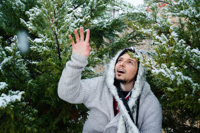 Man wearing warm clothing by snow covered plants