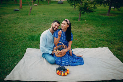 Full length of smiling young woman sitting on grass