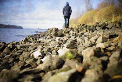 Rear view of man standing on rock in sea