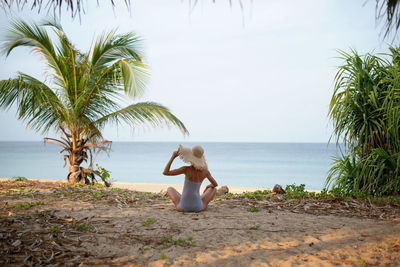 Man sitting at beach against sky