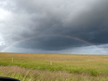 Scenic view of field against rainbow in sky
