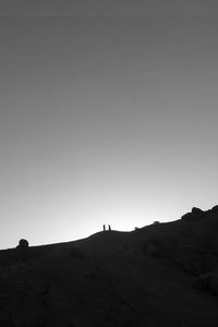 Silhouette people standing on land against clear sky