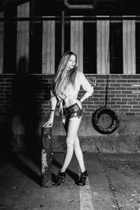 Female model posing against wall at night