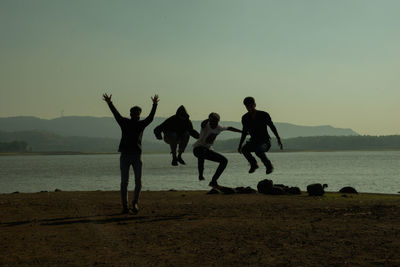 Silhouette people at beach against clear sky