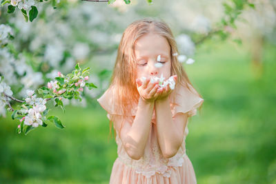 Cute girl blowing flowers outdoors