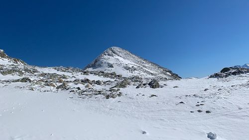 Scenic view of snow covered mountain against blue sky