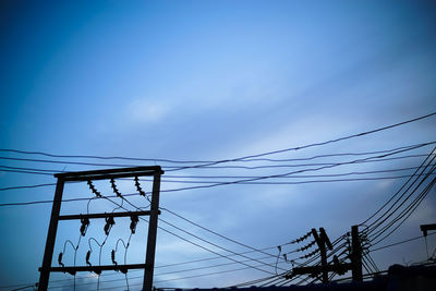 Low angle view of electricity pylon against blue sky