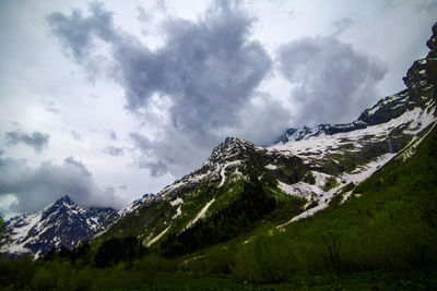 Scenic view of snow covered mountains against cloudy sky