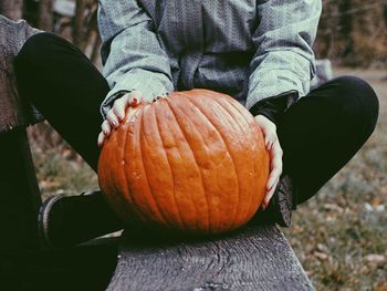 Low section of man holding pumpkin