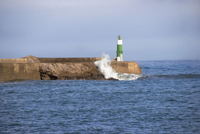 Lighthouse by sea against sky