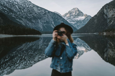 Reflection of woman photographing in lake