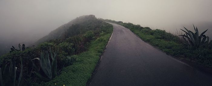 Empty road along landscape against sky