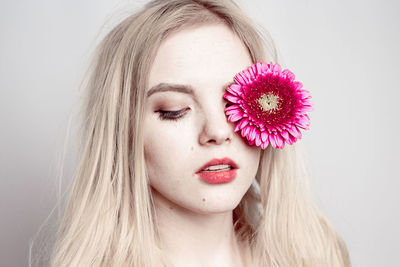 Young woman holding flower against white background