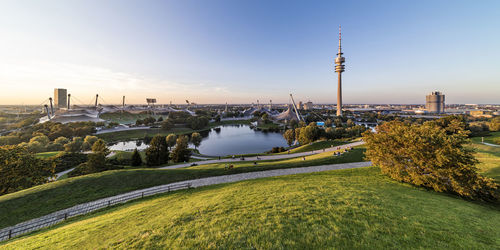 Germany, bavaria, munich, panoramic view of olympic park with olympic tower, bmw building and pond in background