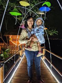 Full length of happy mother and daughter standing against railing