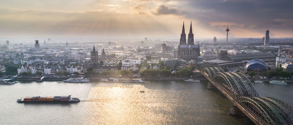 Bridge over river in city against cloudy sky