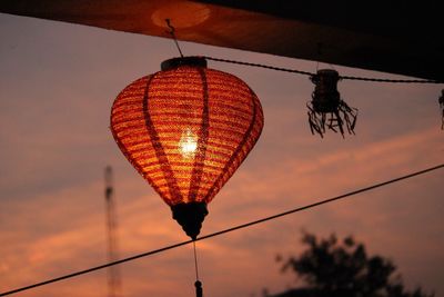 Low angle view of illuminated lamp against sky at sunset