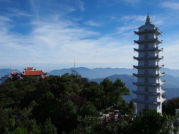 Tower amidst trees and buildings against sky