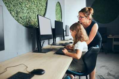 Teacher helping schoolgirl while computer class at primary school. back to school. learning at class